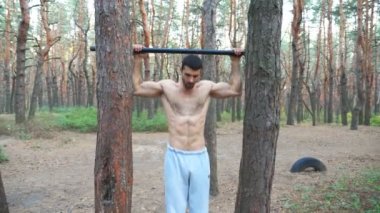 Güçlü adam yatay çubukta egzersiz yapıyor. Barfiks çeken kaslı adam. Sporcu ormanda güç egzersizi yapar. Sporcu eğitimi açık havada. Spor ve aktif yaşam tarzı kavramı.