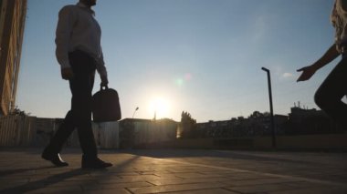 Genç iş arkadaşları şehirde buluşup birbirlerini selamlıyorlar. İki başarılı iş adamı ofis binasının yakınında el sıkışıyor. İş ortakları gelecekteki projelerini dışarıda tartışıyorlar. Dolly vurdu..