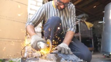 Dairesel testere kullanarak metal öğütüyor. Garajda ya da atölyede işçi kesme işi. Demir kesen adam. Güvenlik için gözlük takan bir tamirci. Parlak kıvılcımlar uçuşuyor. Yavaş çekim,