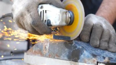 Dairesel testere ve etrafta uçuşan kıvılcımlarla metal işleme hakkında detaylı görüş. Dairesel testere kullanarak metal öğütüyor. Garajda ya da atölyede demir kesen bir işçi. Yavaş çekim. Yakın çekim..