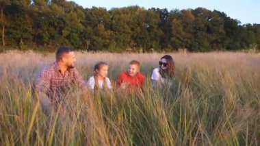 İki çocuklu genç bir aile Meadow 'da birlikte vakit geçiriyor. Küçük çocukları olan anne ve baba çimde oturup güzel doğanın tadını çıkarıyorlar. Aile mutluluğu kavramı. Dolly vurdu..