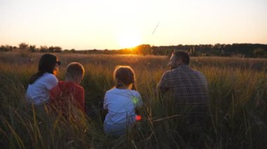 Küçük çocukları olan genç ebeveynler Meadow 'da birlikte vakit geçiriyorlar. İki çocuklu anne ve baba çimde oturuyor ve doğanın tadını çıkarıyorlar. Aile mutluluğu kavramı. Dolly vurdu..