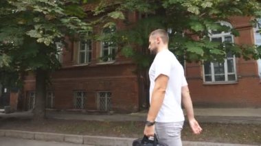 Gündelik giysiler içinde genç bir işadamı ya da öğrenci şehir sokaklarında dolaşıp saatine bakıyor. Evrak çantalı, kendine güvenen bir adam ofise geç geldiği için kontrol ediyor. Adam işe gidiyormuş. Yavaş çekim.