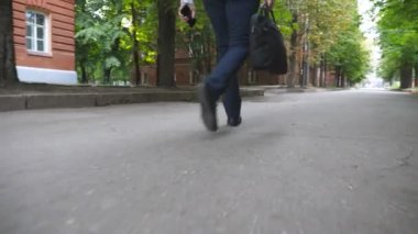 Kamera, kentsel cadde boyunca resmi kıyafetler giyen tanınmayan girişimcilerin bacaklarını takip ediyor. Elinde telefon ve çanta olan özgüvenli bir adamın iş merkezine gitmesi. Yavaş çekim.
