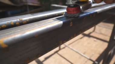 Dairesel testereyle metal işleme. Tamircinin elleri özel bir enstrüman tutuyor ve metali pasdan temizliyor. İşçi dışarıda demir parçaları öğütüyor. Garajda ya da atölyede iş. Yavaş çekim. Yakın çekim..