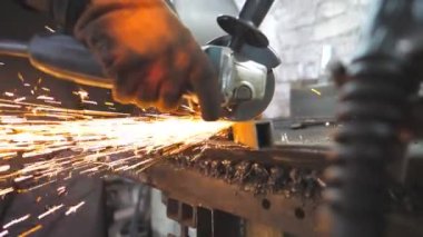 Ustabaşı metal kesmek için testere kesme makinesi kullanıyor. Garajda ya da atölyede çeliği kesen dairesel testereli bir adam. Metal öğüten endüstriyel işçiler. Sıcak metalden kıvılcımlar çıkıyor. Yavaş çekim.