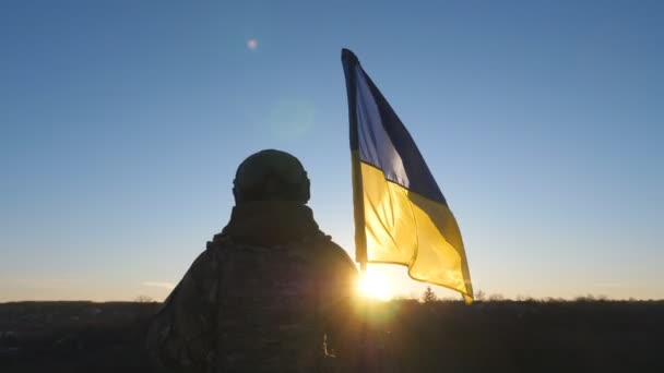 ウクライナの迷彩制服持ち上げフラグの若い女性兵士 ウクライナ軍の女性は日没時に青黄色のバナーを振って丘のピークに立っている ロシアの侵略概念への抵抗 — ストック動画