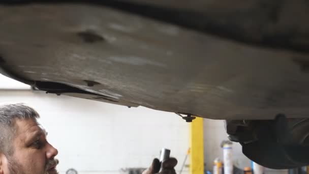전문적 자동차 정비사는 작업장에서 기구로 볼트를 조이는 차고에서 밑에서 일하는 — 비디오