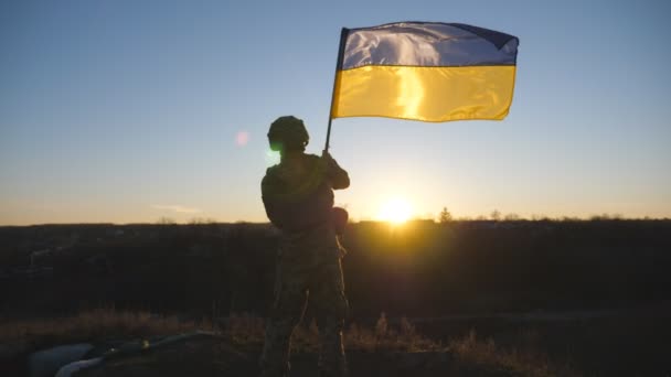 Στρατιωτικός Στολή Κυματίζει Σημαία Της Ουκρανίας Στο Φόντο Του Ηλιοβασιλέματος — Αρχείο Βίντεο