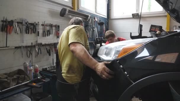 Δύο Μηχανικοί Αφαιρώντας Τον Μπροστινό Προφυλακτήρα Από Αυτοκίνητο Για Την — Αρχείο Βίντεο