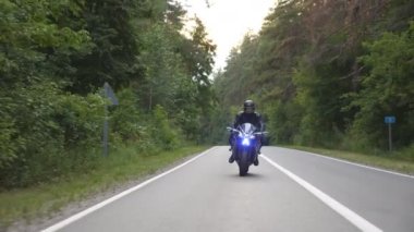 Kırsal Orman Yolu 'nda motosiklet süren bir motosikletli. Motosikletli, kır yolunda motosikletiyle yarışıyor. Yolculuk sırasında bisiklet süren bir adam. Özgürlük yaşam tarzı ve macera kavramı. Yavaş çekim.