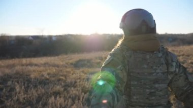 Gün batımında erkek elini tutarak sahada koşarken beni takip edin. Neşeli bayan asker erkek arkadaşını çayırların arasına çekiyor. Mutlu askeri çift kırsalda eğleniyor. POV.