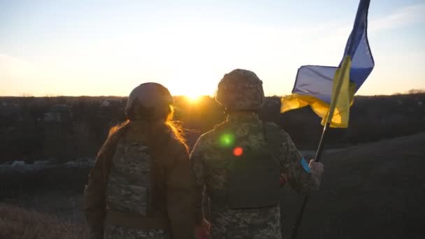 ウクライナ軍の兵士は日没を背景にウクライナの国旗を掲揚した 軍の制服を着た人々が黄色の旗を持ち上げた ロシアの侵略に対する勝利 侵入抵抗概念 — ストック動画