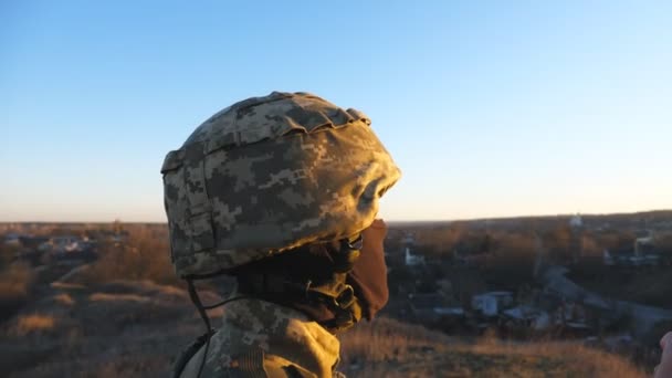 ウクライナ軍兵士のドリーショットは日没を背景に青い黄色の旗を掲げている ウクライナの持ち上げられた国旗と一様に男性の軍隊は丘のピークに立つ 閉じろ — ストック動画