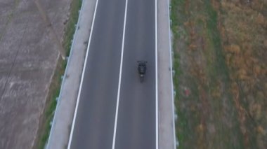 Motosikletli birinin kır yolunda motosikletiyle yarışması. Yolculuk sırasında bisiklet süren bir adam. Havadan bakıldığında, kırsal kesimde motosiklet kullanan bir motosikletli. Özgürlük ve macera kavramı.