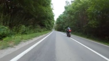 Orman yolundaki motosikletli motorcuları takip edin. Kasklı adam ormanın yakınındaki kırsal yolda modern spor motosiklet yarışı yapıyor. Yolculuk sırasında ya da yolculukta bisiklet süren adam. Özgürlük kavramı.