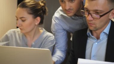 Ofisteki bilgisayardaki istatistiksel verileri inceleyen genç iş arkadaşları. Profesyonel yöneticiler masada oturan iş geliştirme üzerinde çalışırlar. Şirket projesi için iş arkadaşları planlama stratejisi.