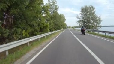 Motosikletli modern spor motosikletli göl kenarındaki yolda. Motosikletli, yaz günü baraj yolunda motosikletiyle yarışıyor. Yolculuk sırasında bisiklet süren bir adam. Özgürlük ve macera kavramı. Hava görüntüsü.