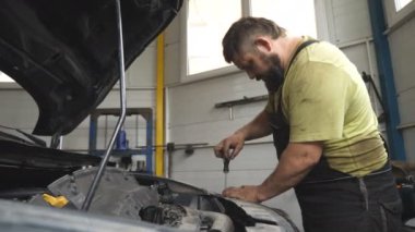 Atölyede ya da serviste tamir edilmeden önce otomobil tamircisi arabayı söküyor. Profesyonel tamirci araç kaputu altında çalışır. Otomobili özel bir aletle tamir eden adam. Bakım ve tanı kavramı