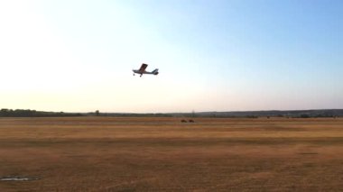 Arka planda güneş patlamaları olan küçük özel bir uçak havaalanında uçuyor. Hafif uçak tırmanıyor. Mavi gökyüzüne doğru hareket eden dönen pervaneli tek motorlu ultrallight uçak. Havacılık kavramı