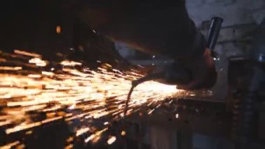 Ustabaşı metal kesmek için testere kesme makinesi kullanıyor. Garajda ya da atölyede çeliği kesen dairesel testereli bir adam. Metal öğüten endüstriyel işçiler. Sıcak metalden kıvılcımlar çıkıyor. Yavaş çekim.