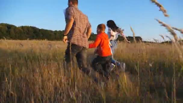 Šťastní Rodiče Dětmi Běhají Travnatým Polem Drží Ruce Při Západu — Stock video