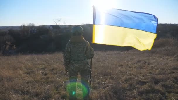 Γυναίκα Στρατιωτική Στολή Στέκεται Υψωμένη Σημαία Της Ουκρανίας Στο Πεδίο — Αρχείο Βίντεο