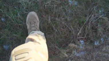 Ukraynalı kadın askerlerin kırsal alandaki kuru çimlerin arasından kahverengi çizmelerle geçmesine bakış açısı. Askeri ayakkabılı genç asker kız bacakları ekilmemiş tarlalarda yürüyor. Ukrayna 'da Savaş