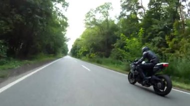 Orman yolunda motosiklet yarışı yapan bir motosikletli. Ormanın yakınındaki kırsal yolda kasklı bir adam spor motosikletine biniyor. Yolculuk sırasında bisiklet süren adam. Özgürlük ve macera kavramı. Hava görüntüsü