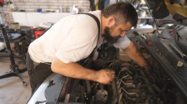 Tamirci oto servisinde araba bakımı yapıyor. Garajda kaputun altında çalışan profesyonel bir tamirci. Sakallı adam atölyede otomobil motorunu kontrol ediyor. Otomobil tanılama kavramı