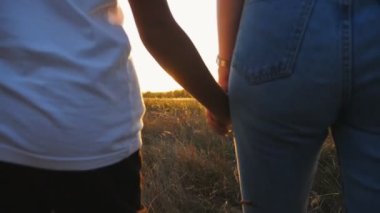 Anne ve kızın kadın elleri gün batımında çimen tarlasında birbirlerine sarılıyorlar. Anne çocuğuyla yaz otlağında yürüyor. Arka planda güzel bir güneş ışığı var. Aile sevgisi kavramı. Kapat..