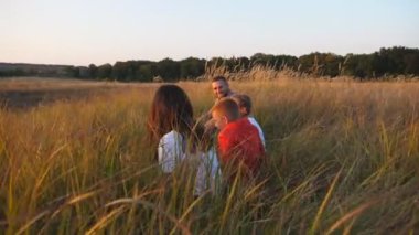 İki çocuklu genç bir aile Meadow 'da birlikte vakit geçiriyor. Küçük çocukları olan anne ve baba çimde oturup güzel doğanın tadını çıkarıyorlar. Aile mutluluğu kavramı. Dolly vurdu..