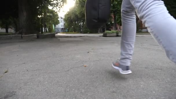 早上穿着休闲装的年轻人的腿穿行在城市公园里 商人因为工作迟到而带着旅行袋慢跑 一个难以辨认的家伙在办公室里匆忙赶忙 通勤的概念 慢动作 — 图库视频影像