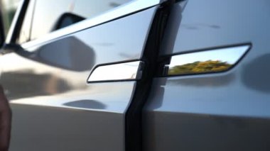 Erkek eli kapıyı açar ve modern arabaya biner. Otomobilin kapısını açmak için düğmeye basan adam. Adam otomatiğe oturuyor. Çağdaş teknolojiler kavramı. Yavaş Hareketi Kapat.