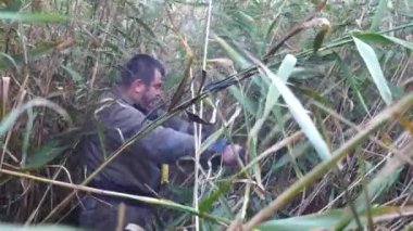 Erkek itfaiyeci kırsalda uzun ve kuru otların arasından geçiyor. Üniformalı profesyonel itfaiyeci bitkilerin arasında yürüyor. Yanabilir bir arazide hareket eden genç bir güvenlik görevlisi. Yavaş çekim.