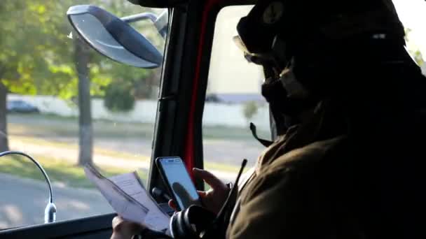Ein Männlicher Feuerwehrmann Fährt Mit Dem Handy Auf Einem Feuerwehrauto — Stockvideo
