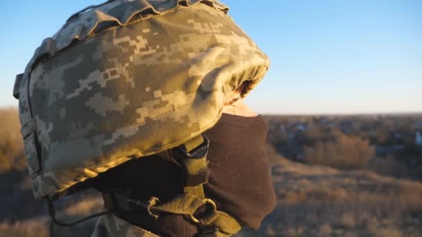年轻军人在日落时满怀希望的形象 男兵头戴头盔 头戴巴拉克拉瓦 凝视着乡村 俄罗斯和乌克兰之间的战争 抵抗入侵的概念 — 图库视频影像