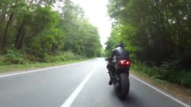Orman yolunda motosiklet yarışı yapan bir motosikletli. Ormanın yakınındaki kırsal yolda kasklı bir adam spor motosikletine biniyor. Yolculuk sırasında bisiklet süren adam. Özgürlük ve macera kavramı. Hava görüntüsü.