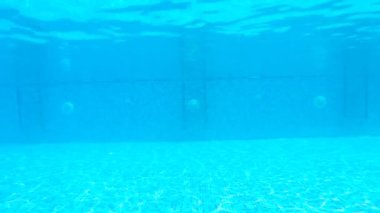 Havuzda suyun altında yüzen seksi bir kadın. Havuzda yüzen kırmızı bikinili bir kız. Bayan turist dinlenme yerinin keyfini çıkarıyor. Su altı görüntüleri. Tatil konsepti. Yavaş çekim.