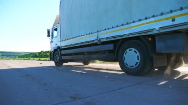 Boş otoban boyunca giden ve malları taşıyan kargo karavanı olan kamyonun yan görüntüsü. Kamyon kırsal yoldan geçerek hedefe gidiyor. Kargo taşıma konsepti. Yavaş çekim.