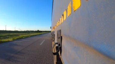 Otoyolda kamyon sürüyor. Kamyon kırsaldan geçiyor. Traktör römorkundan asfalt yola giden araba trafiğine bakış açısı. Taşımacılık ve ticari araç kavramı. Zaman Süreleri.