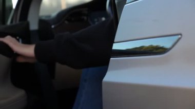 Adam kapıyı açıyor ve modern arabadan iniyor. Adam otomobilin kapısını açtı. Elektrikli otomotiv çıkışı. İş seyahati ya da anlaşma. Çağdaş teknolojiler kavramı. Yavaş Hareketi Kapat.