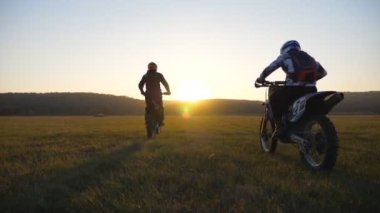 Motosikletliler geniş alanda motosikletleriyle geziyorlar. Arkadaşlar gün batımında dışarıda dinlenip güçlü motosikletler kullanıyorlar. Motorcular gezinin tadını çıkarıyor. Olağanüstü spor konsepti. Manzara manzarası.