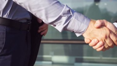 Ofis binası yakınlarında başarılı bir anlaşma yaptıktan sonra kendine güvenen iki işadamı el sıkışıyor. Şehir ortamında birbirlerini tebrik eden genç meslektaşlar. İş ortaklarının el sıkışması. Yavaş çekim.