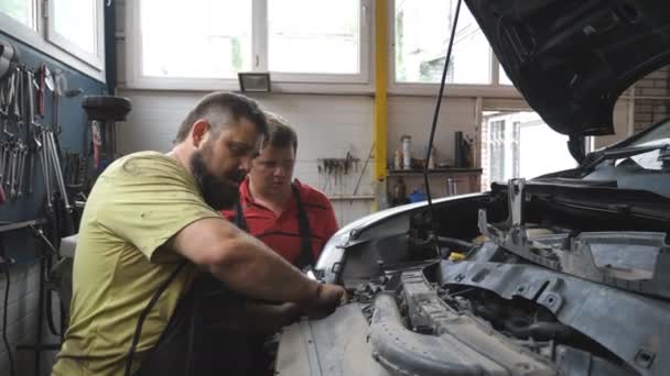 Δύο Επισκευαστές Επισκευάζουν Αυτοκίνητο Στο Συνεργείο Στην Υπηρεσία Μηχανική Λειτουργεί — Αρχείο Βίντεο