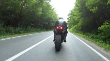 Orman yolunda motosiklet yarışı yapan bir motosikletli. Ormanın yakınındaki kırsal yolda kasklı bir adam spor motosikletine biniyor. Yolculuk sırasında bisiklet süren adam. Özgürlük ve macera kavramı. Hava görüntüsü.