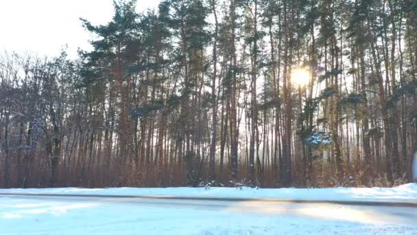 雪の中を白い車で高速氷の道覆われた乗馬 晴れた日には冬の森の中を空の田舎道を行くSuv 自動風光明媚な風景の道を移動します トラベルコンセプトトップビュードローン撮影 — ストック動画