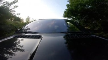 Genç çift kırsalda araba sürmekten zevk alıyor. Erkek arkadaş ve kız arkadaş yaz akşamı otomobille seyahat ediyorlar. Arka planda manzaralı otomobil sürüşü. Yolculuk konsepti. Ön görünüm.