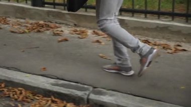 Sabahları sokak ortasında koşuşturan günlük giysili genç adam bacakları. İş adamı, işe geç kaldığı için koşuyor. Ofise aceleyle gelen tanınmayan bir adam. İşe gidip gelme kavramı. Yavaş çekim.