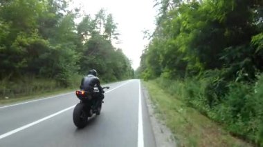 Orman yolunda motosiklet yarışı yapan bir motosikletli. Ormanın yakınındaki kırsal yolda kasklı bir adam spor motosikletine biniyor. Yolculuk sırasında bisiklet süren adam. Özgürlük ve macera kavramı. Hava görüntüsü.